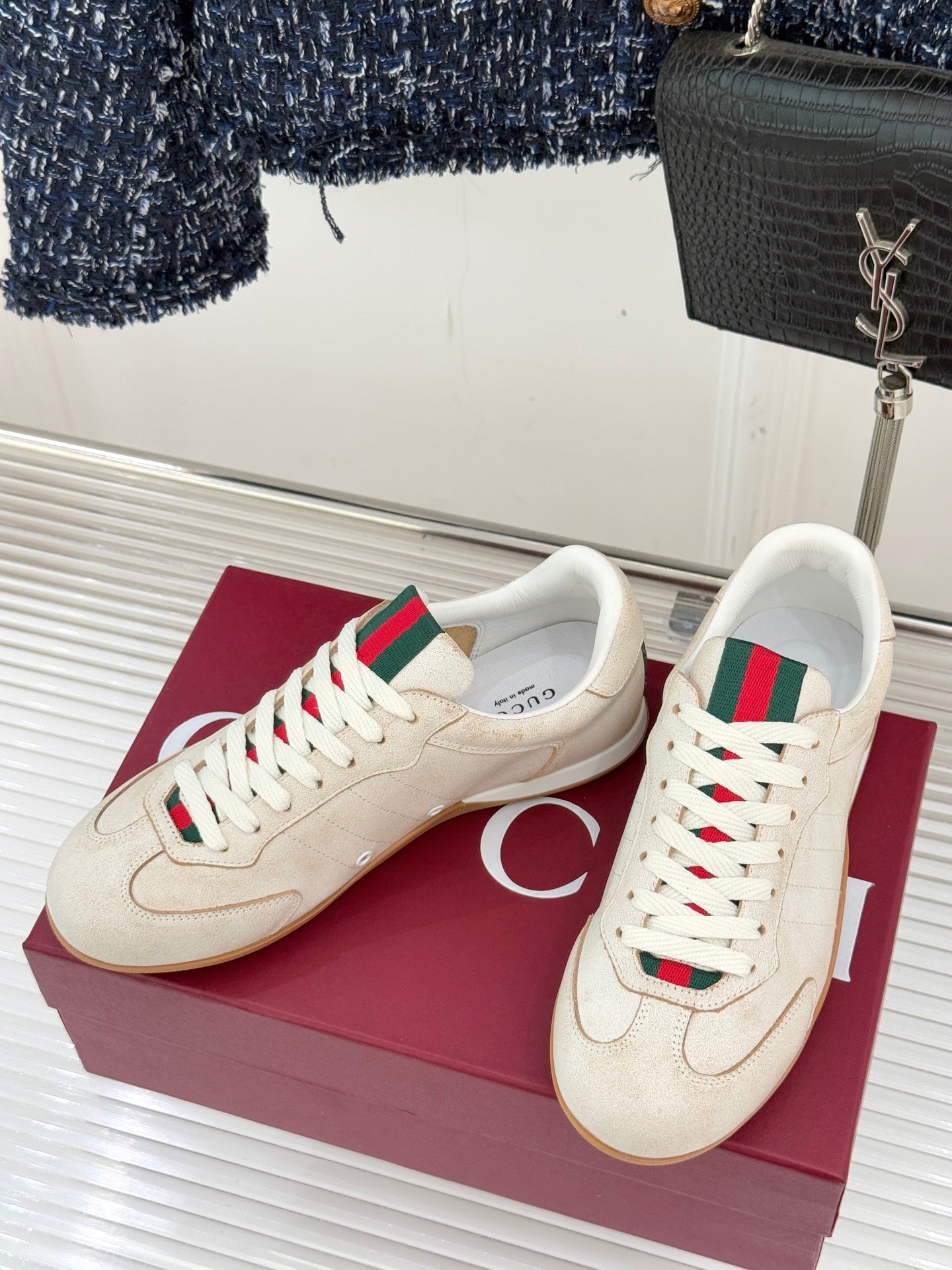 Pair of cream sneakers with white laces, green-red web detail, gum outsole