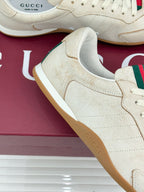 Cream sneaker upper detail with suede-like texture, white laces, gum sole