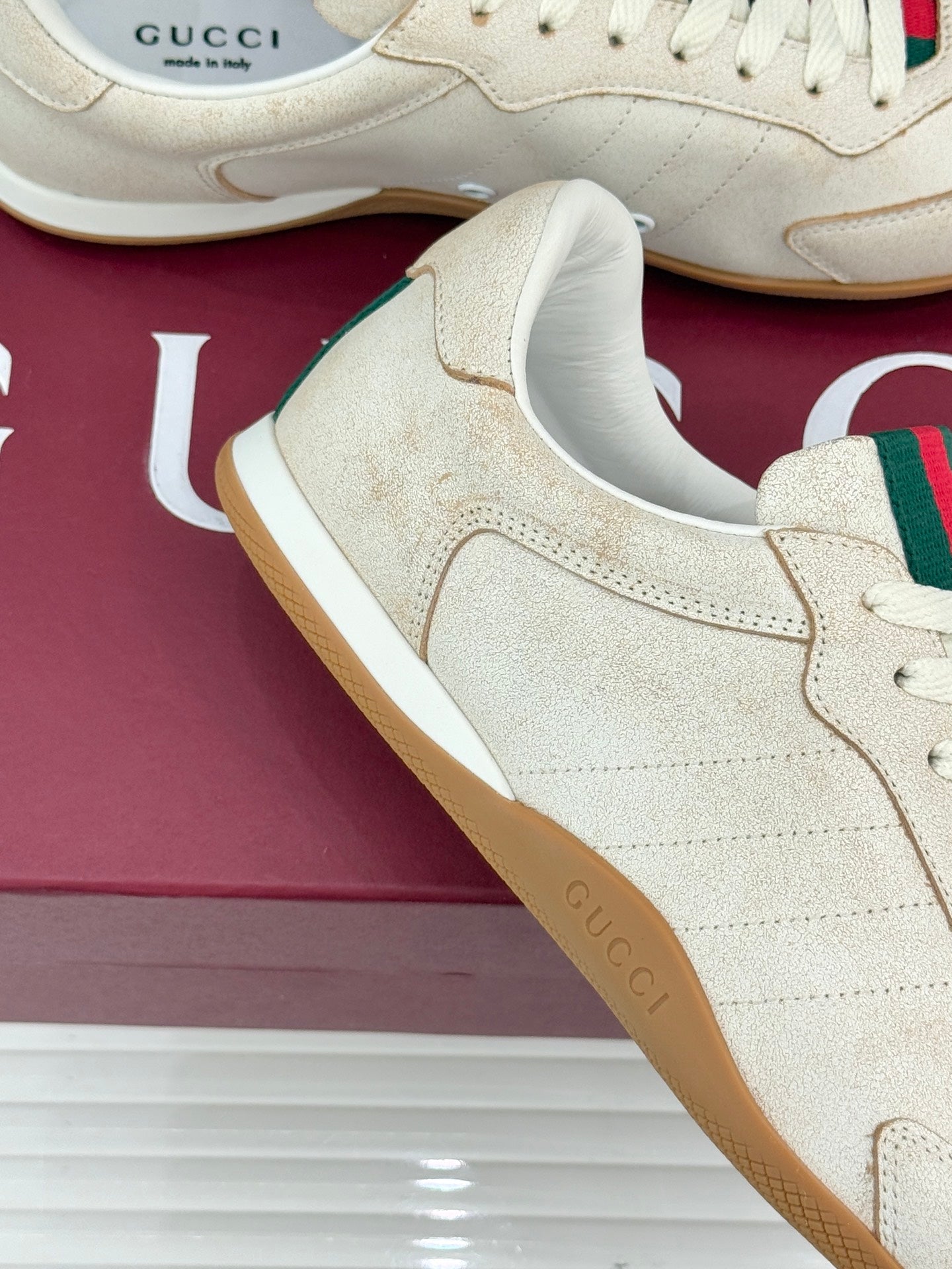 Cream sneaker upper detail with suede-like texture, white laces, gum sole