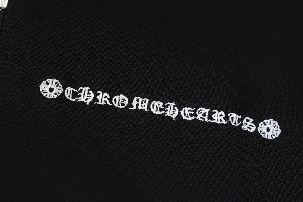 Black hoodie chest emblem with decorative lettering and small floral accents