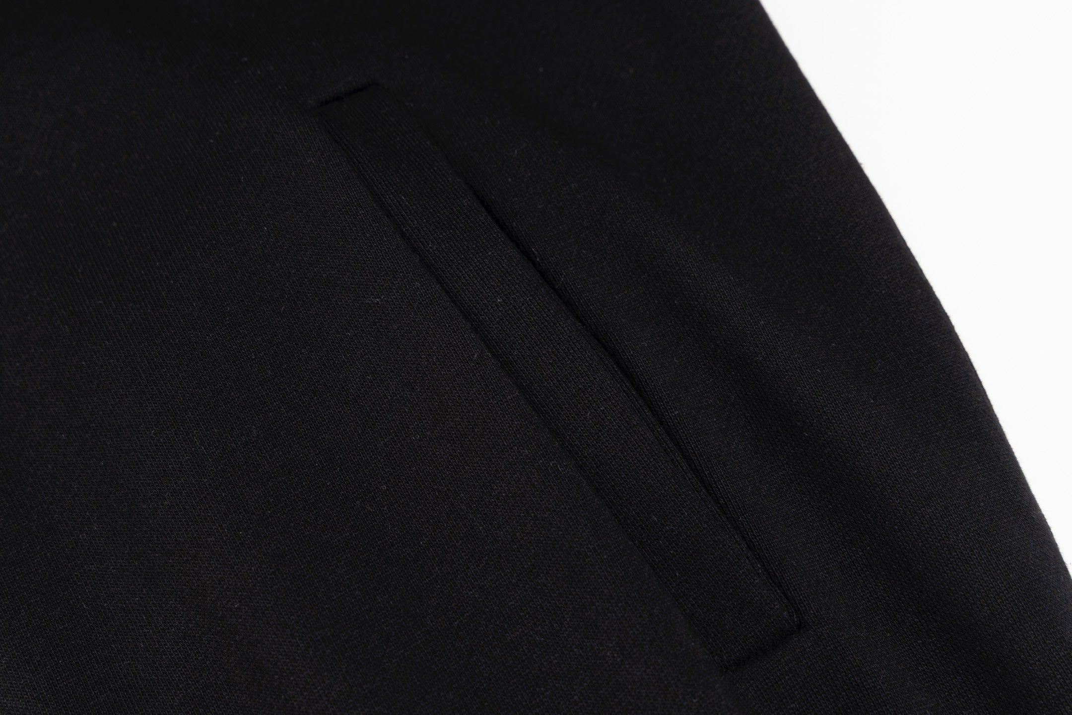 Black hoodie side seam and panel stitching detail near the hem