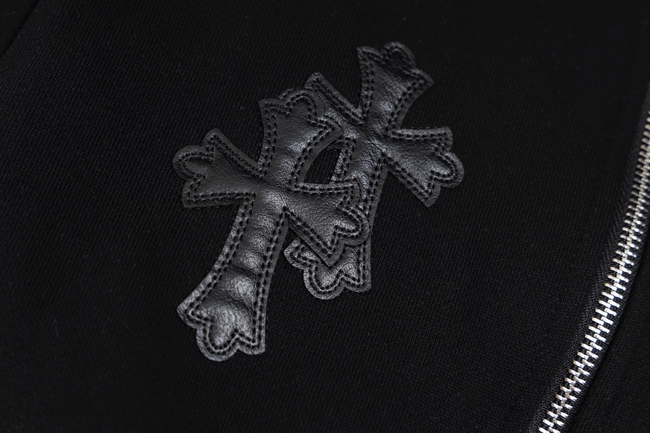 Black hoodie sleeve cross embroidery with textured stitched edges