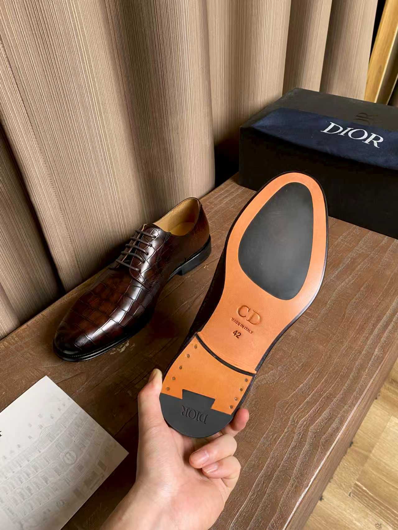 Dior unisex oxford shoe in hand showing orange CD logo insole card