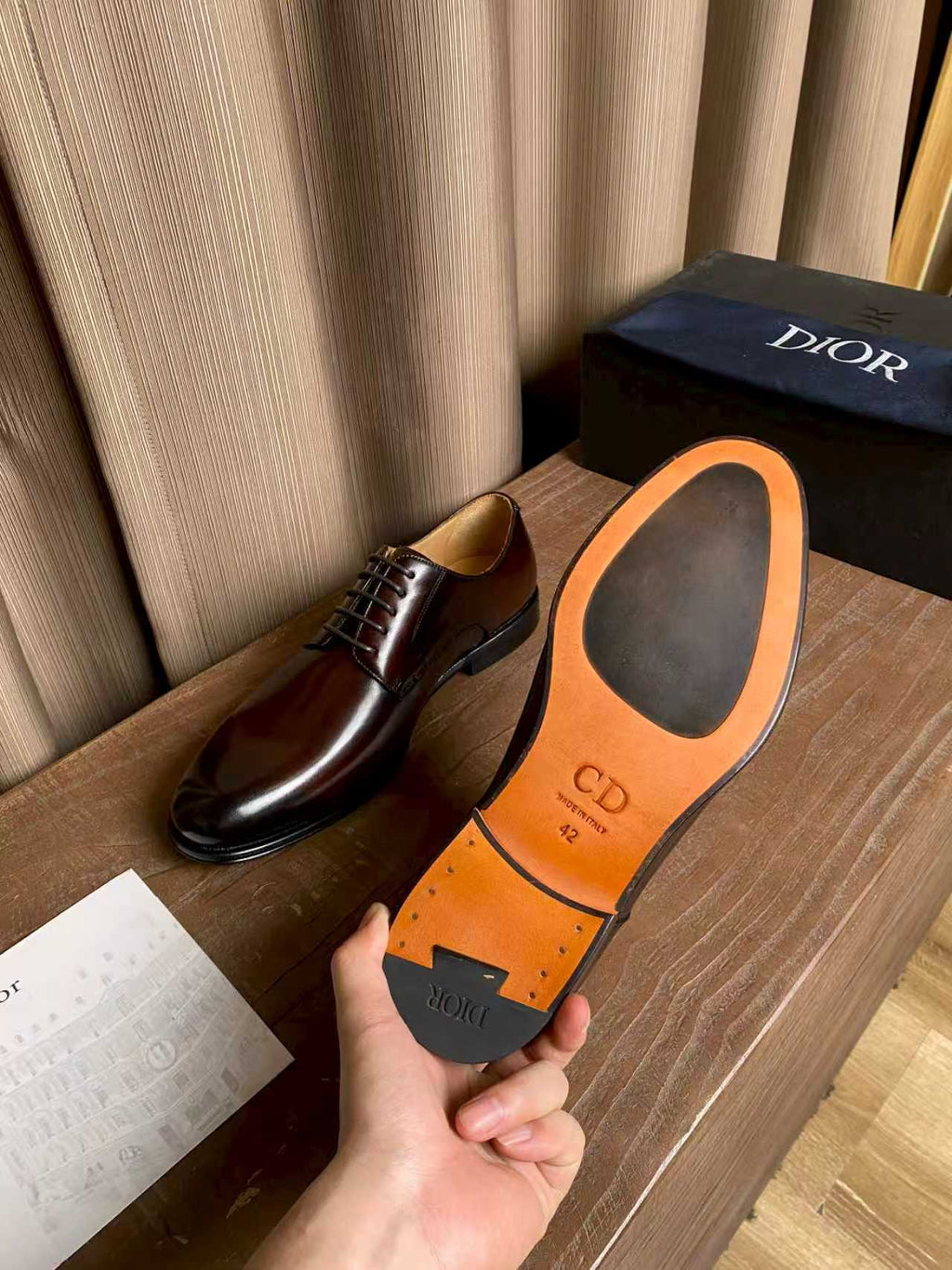 Dior unisex shoes showing orange sole with “CD” logo; dark brown upper