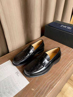 Black leather loafers with embossed texture and silver-tone buckle strap