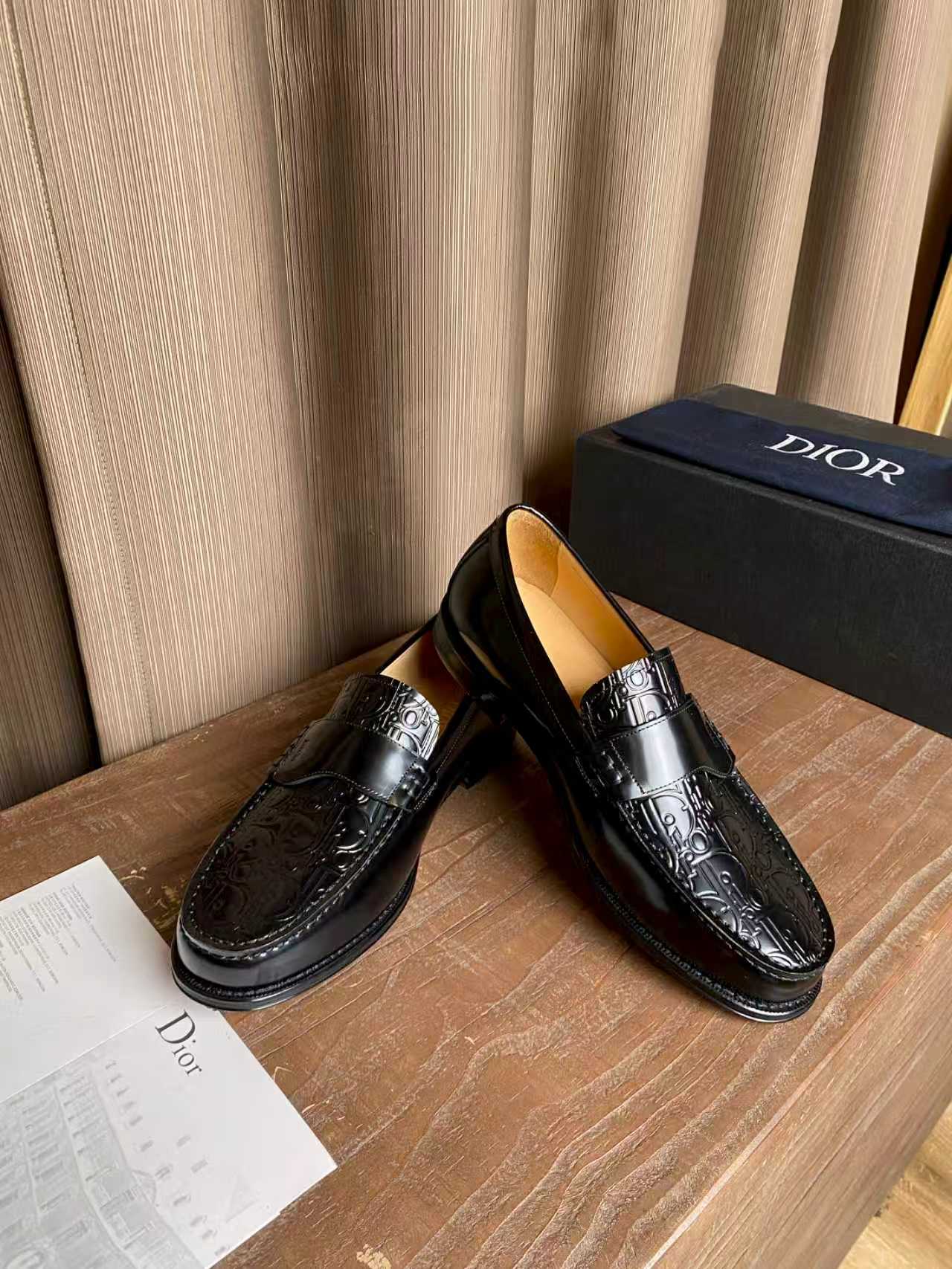 Black leather loafers with decorative embossed trim and metal buckle detail