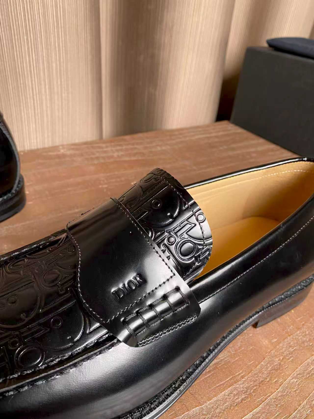 Close-up black leather loafer with embossed strap and silver-toned buckle detail