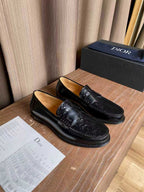 Black leather loafers with embossed detailing and silver-tone buckle hardware