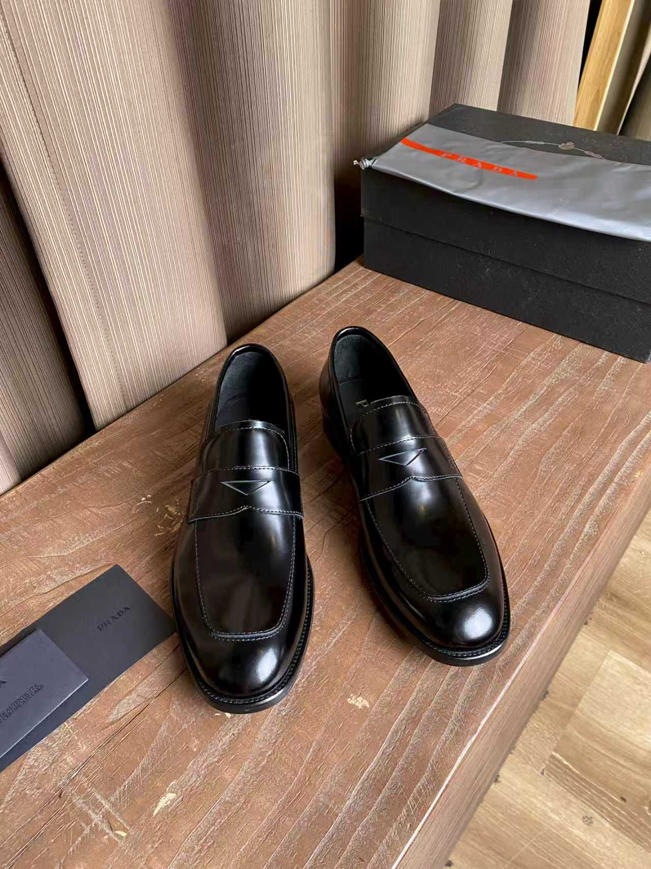 Prada unisex black leather loafers with stitched strap detail and polished finish