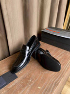 Prada unisex black leather loafers, side view with rounded toe and stitched panels