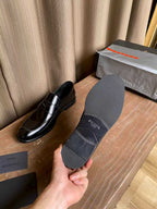 Prada unisex leather loafers and gray dust cover, shown with brand text on cover