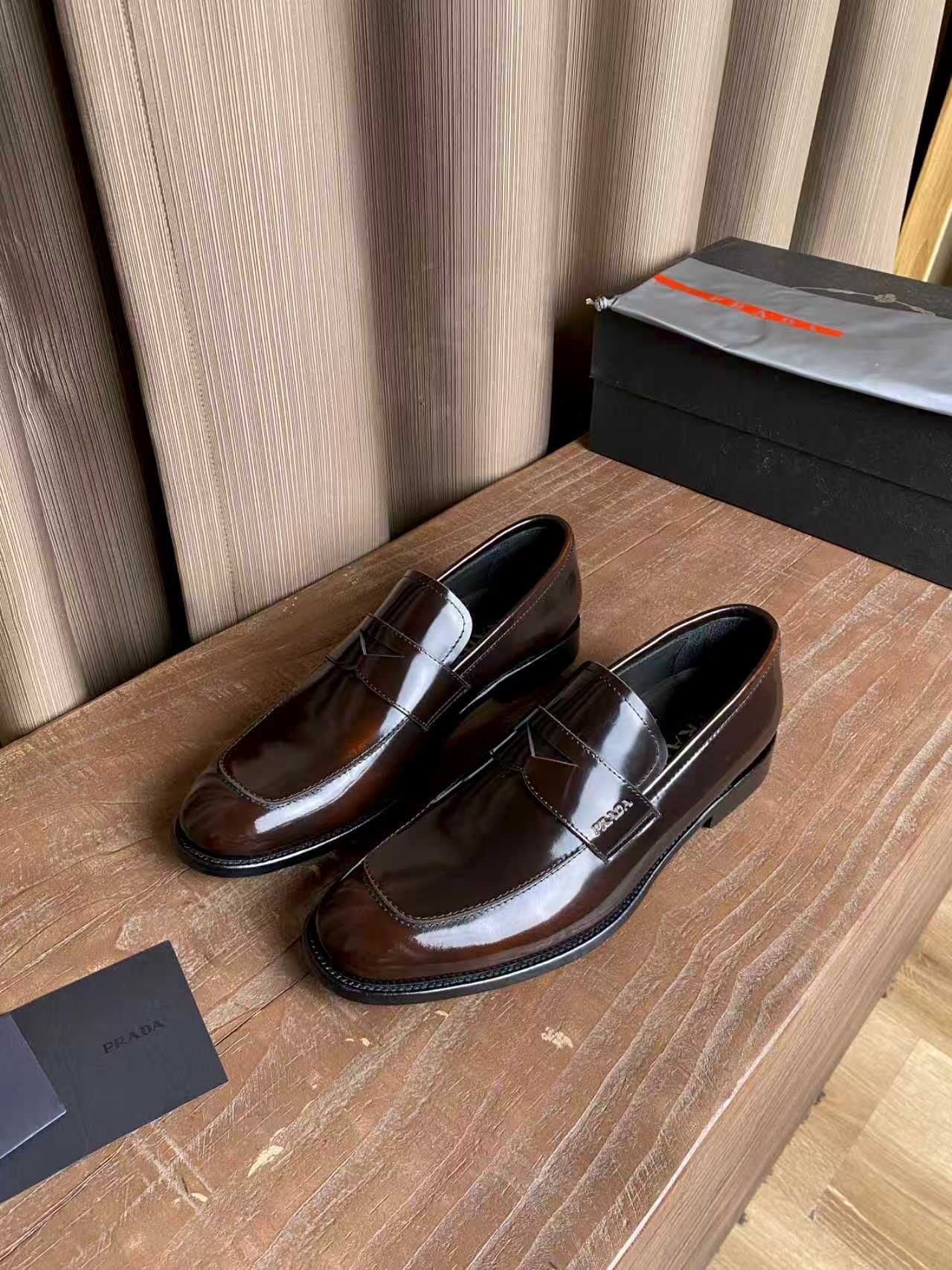 Brown patent leather loafers with glossy finish and stitched apron detail