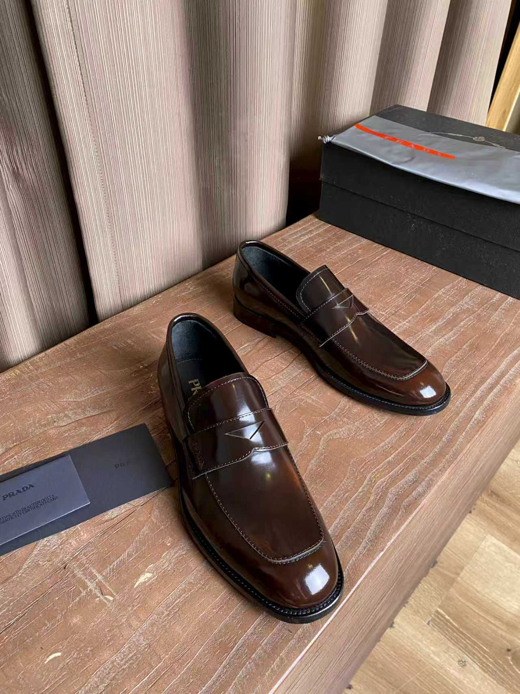 Brown patent leather slip-on loafers with apron stitching and dark rubber sole