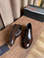 Brown glossy leather loafers with apron stitching and padded collar