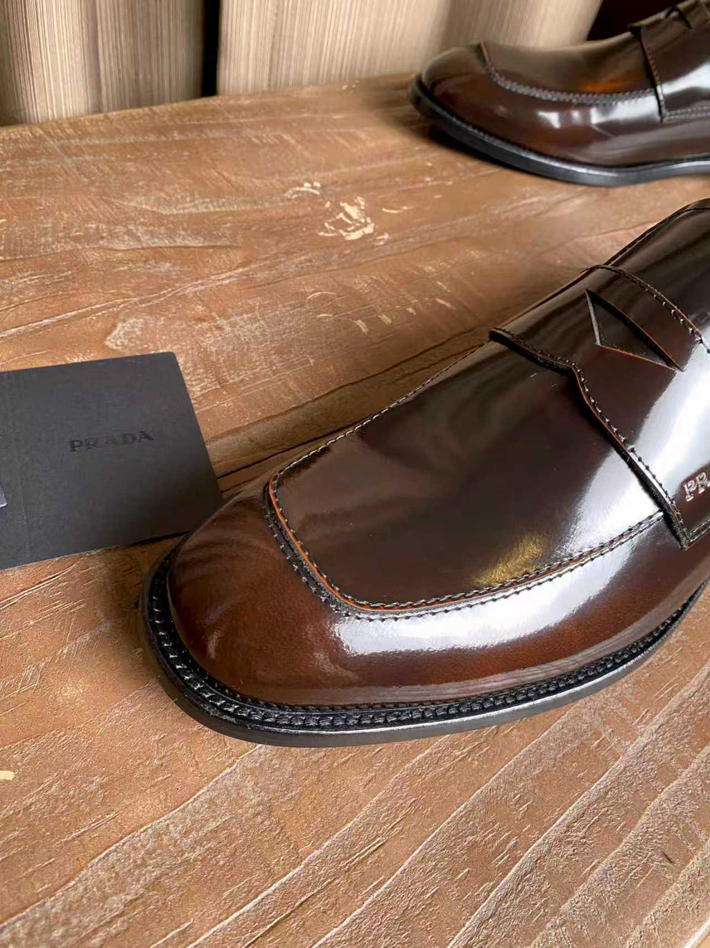 Brown patent leather loafer with glossy upper and contrast-stitched edge