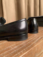 Prada unisex black leather loafers, smooth toe and back heel close-up
