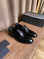 Prada unisex black leather loafers, side view with stitched vamp and logo badge