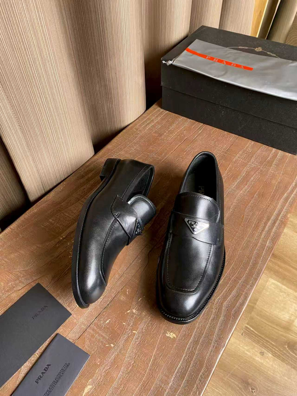 Prada black leather loafers, front view with logo accent on strap