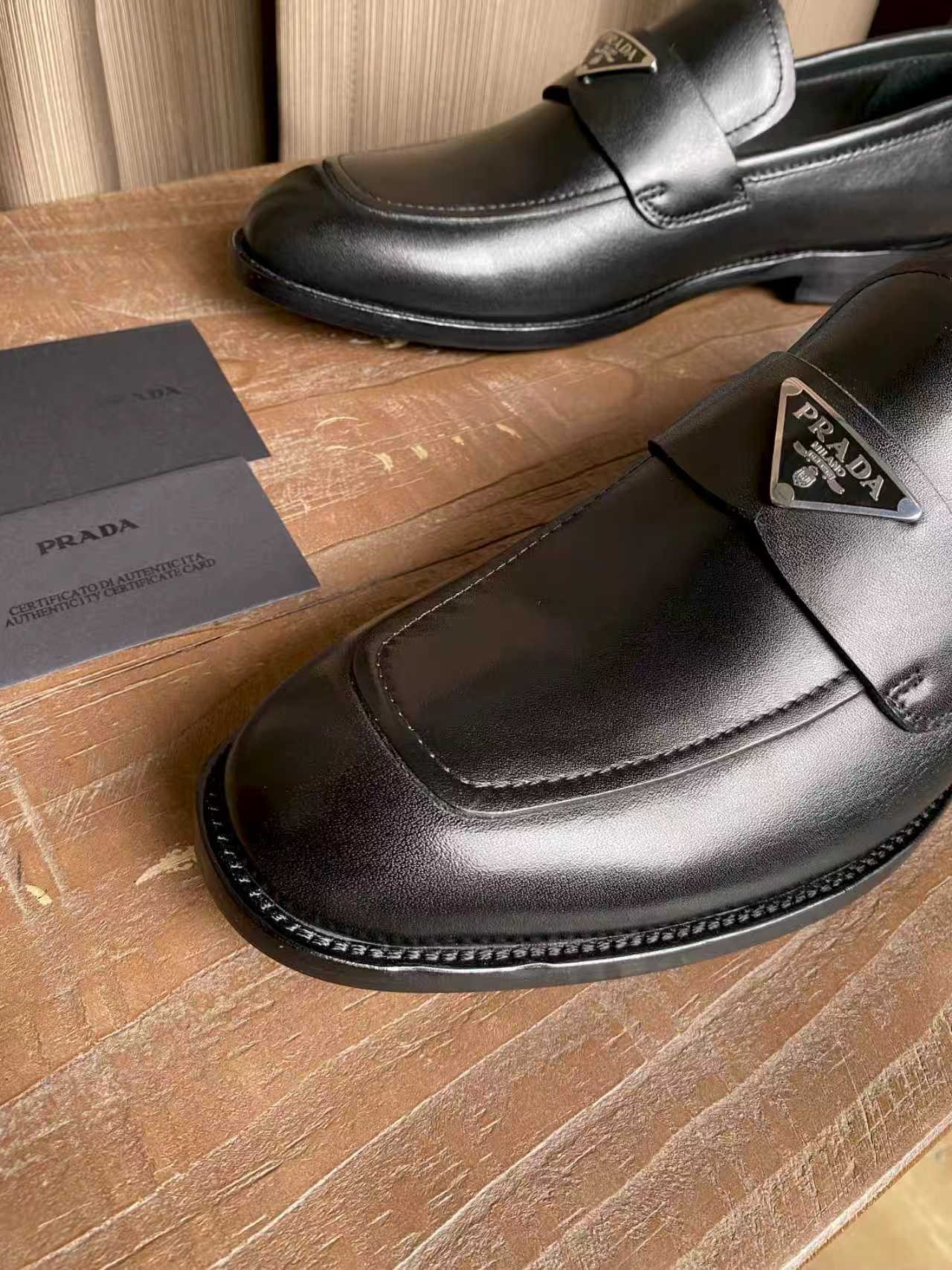 Prada black leather loafer detail, metal logo badge and moc-toe stitching
