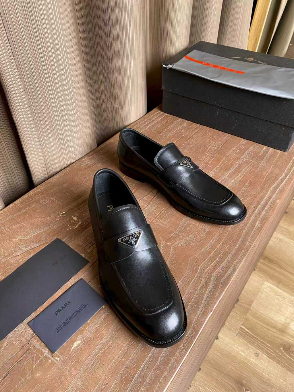 Prada black leather loafers, angled view of the pair with logo tag detail