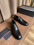 Prada black leather loafers, angled view of the pair with logo tag detail