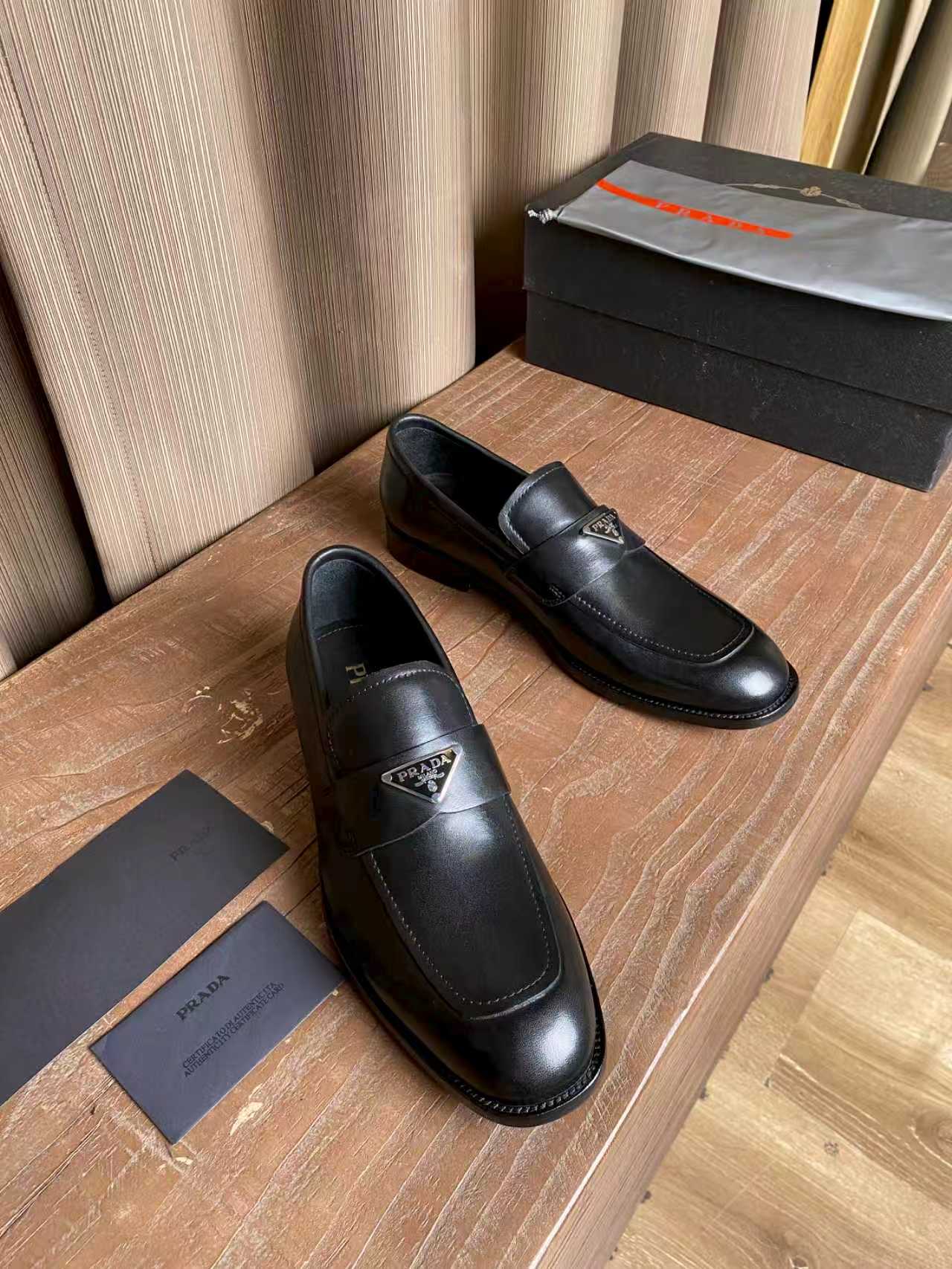 Prada black leather loafers, angled view of the pair with logo tag detail