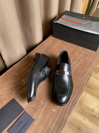 Prada unisex leather loafers shown from side, dark black with stitched sole