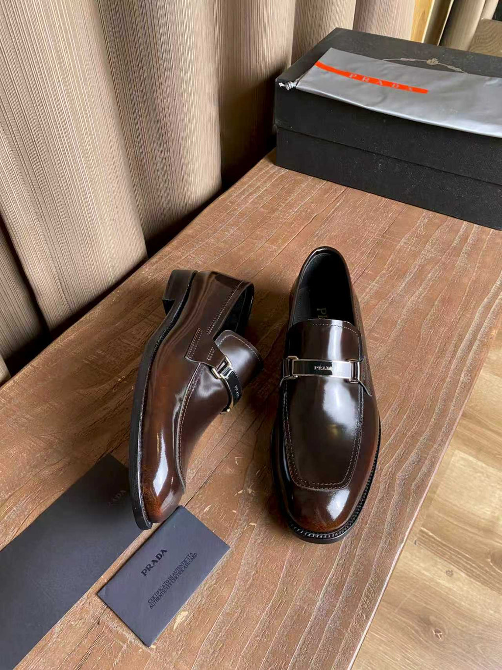 Prada unisex leather loafers, dark brown gloss with silver buckle strap, side angle