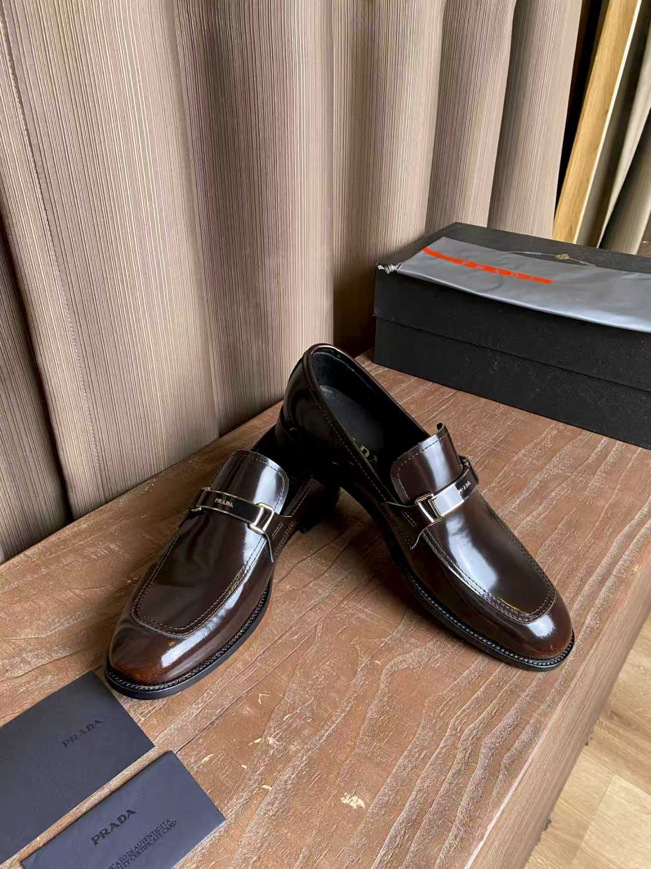 Prada unisex leather loafers, dark brown gloss with silver buckle strap, angled view