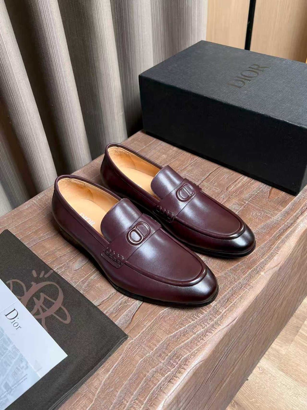 Burgundy leather loafers with front D-shaped logo detail and stitched seams