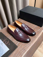 Burgundy leather loafers with front D-shaped logo detail and stitched seams