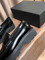 Black patent leather loafer side view with thick platform sole and stitching