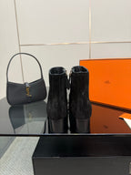 Black women’s ankle boots with buckled straps, shown near a matching tote