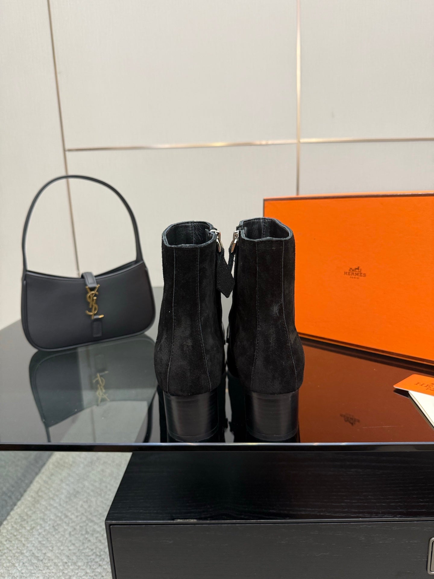 Black women’s ankle boots with buckled straps, shown near a matching tote
