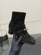 Black women’s ankle boot with buckled strap across the shaft and block heel