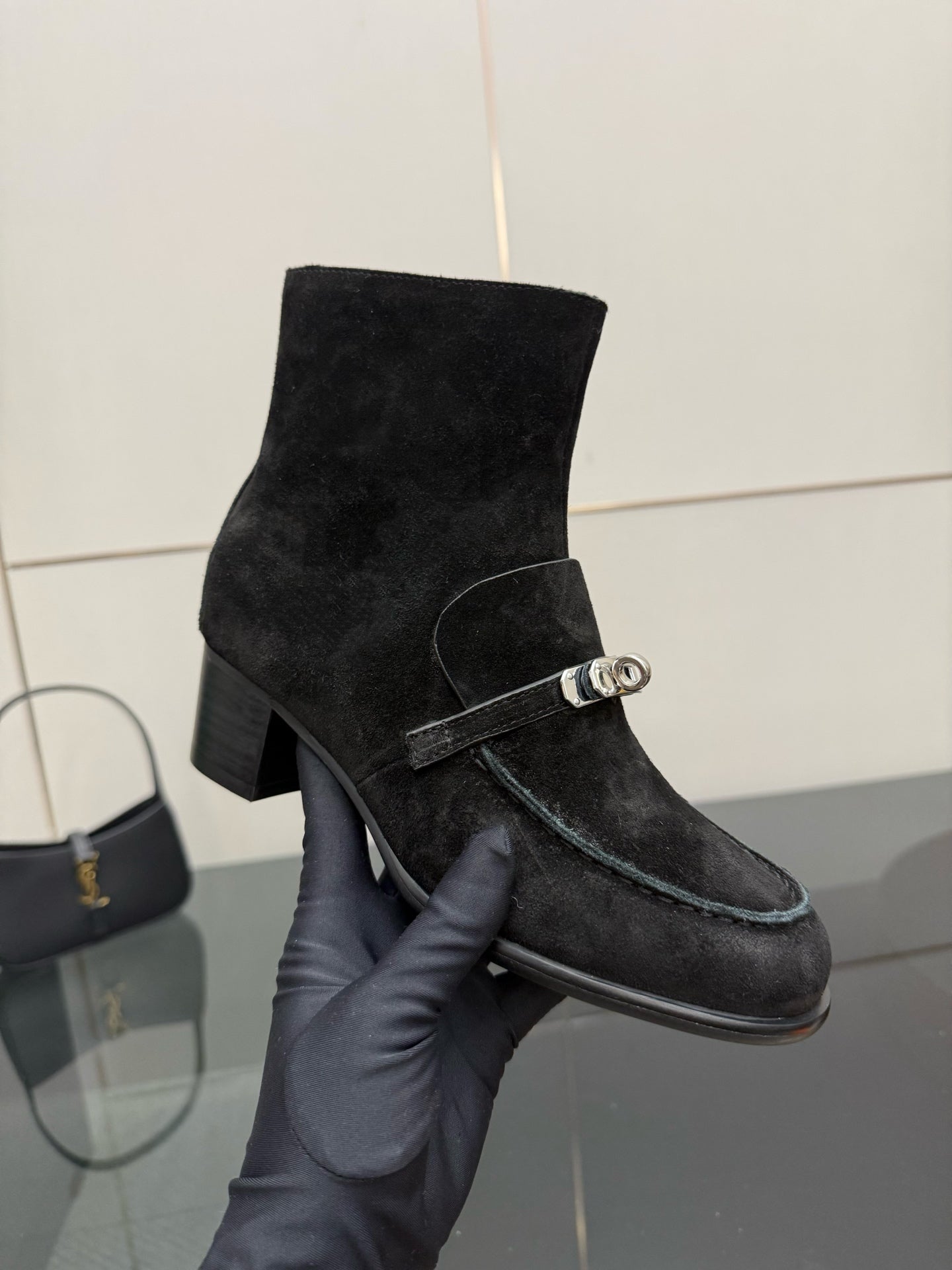 Black women’s ankle boot with buckled strap across the shaft and block heel
