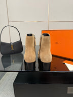 Tan suede ankle boots with silver buckles and block heels standing upright.