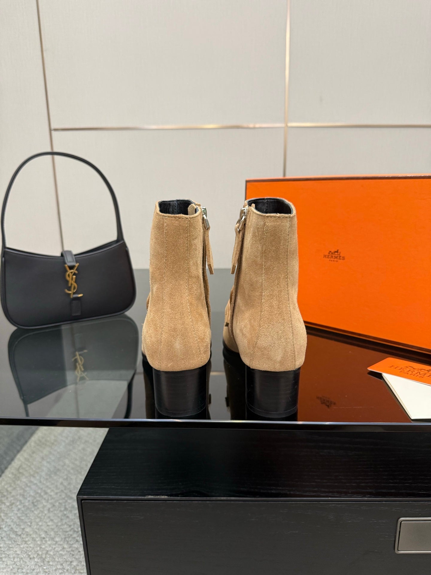 Tan suede ankle boots with silver buckles and block heels standing upright.