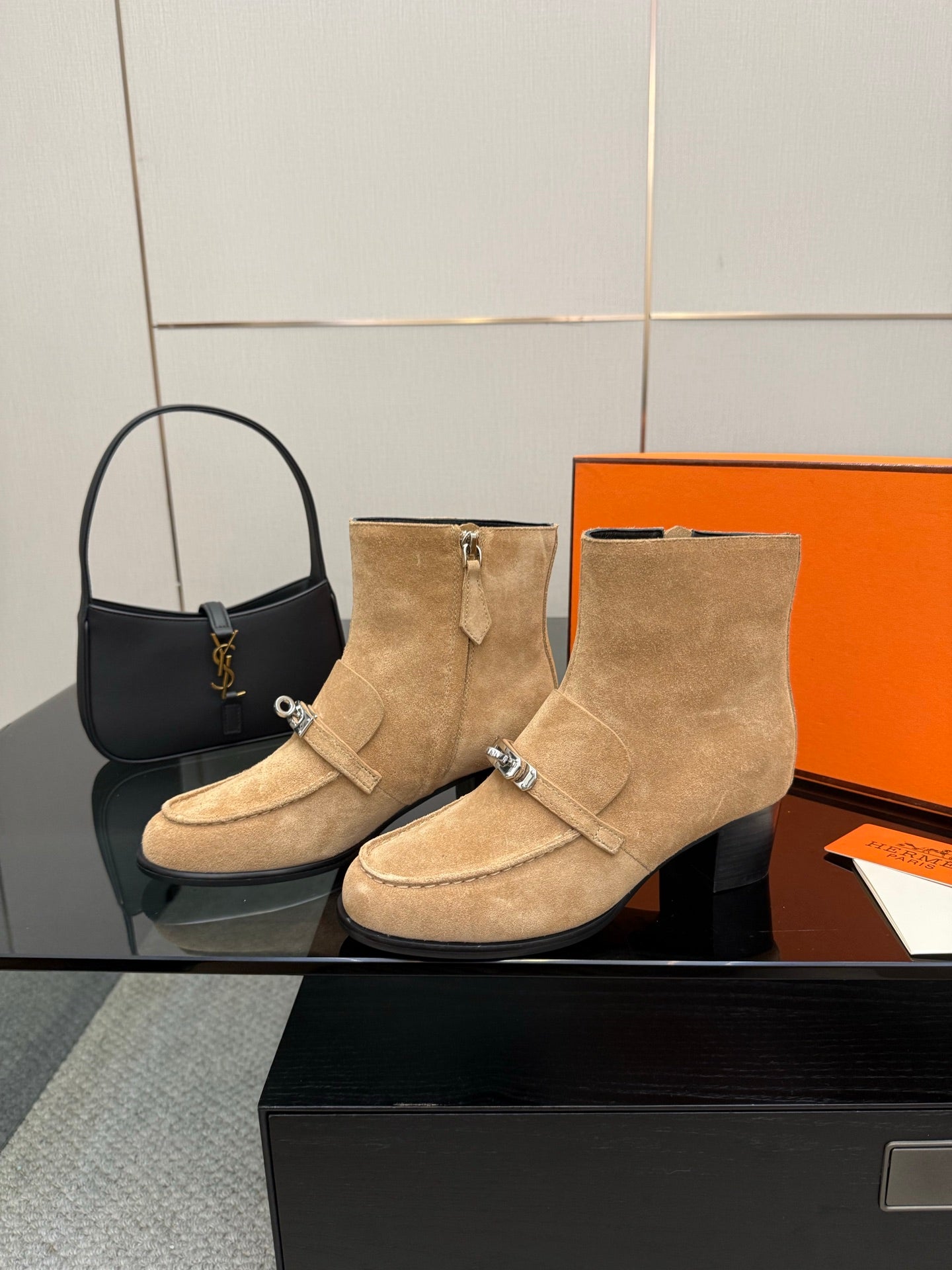Women’s tan suede ankle boots with wide strap, silver buckle, and block heel.