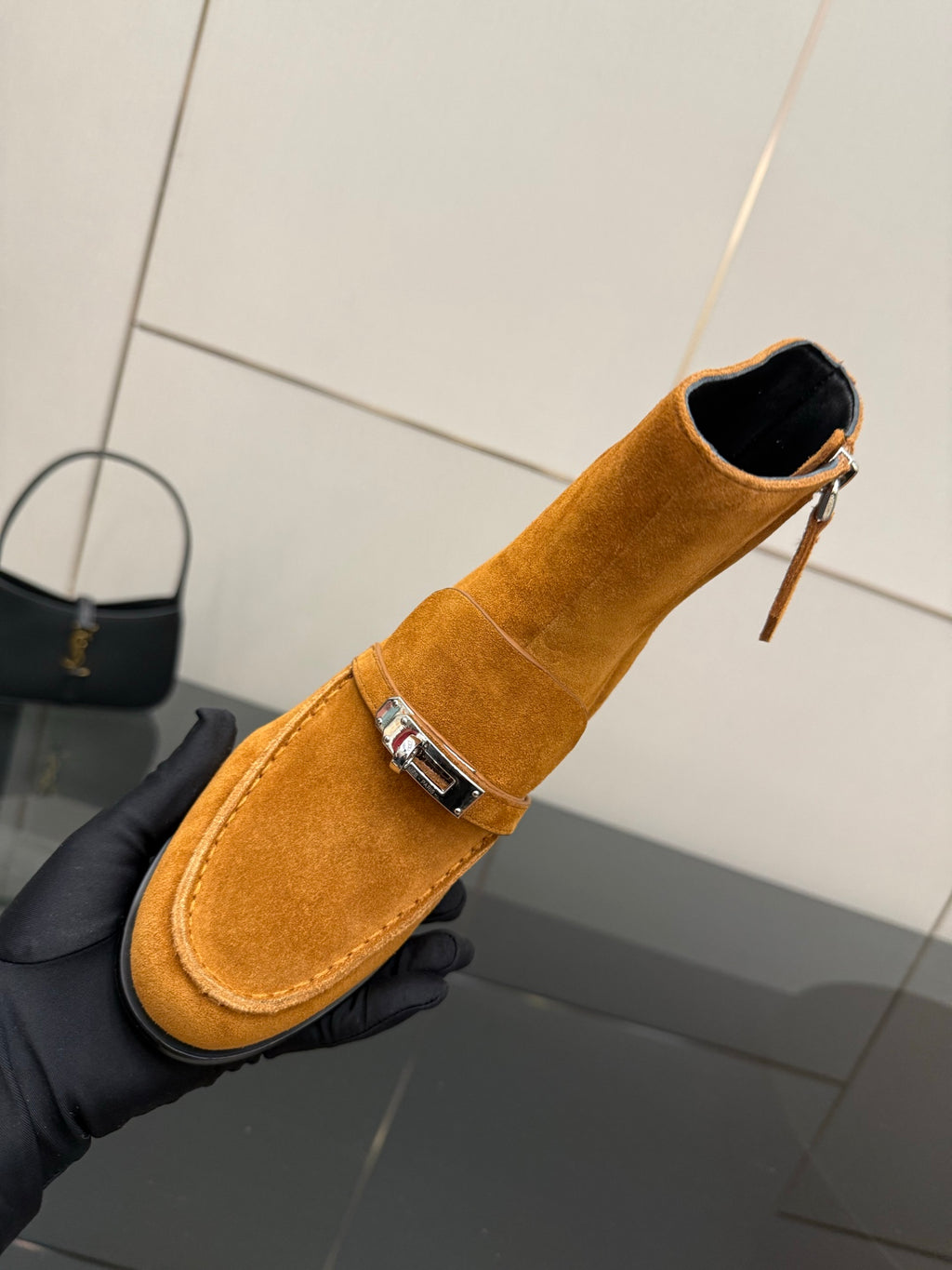 Tan suede ankle boot with zipper closure and buckle strap, close-up side view.