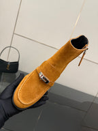 Tan suede ankle boot with zipper closure and buckle strap, close-up side view.