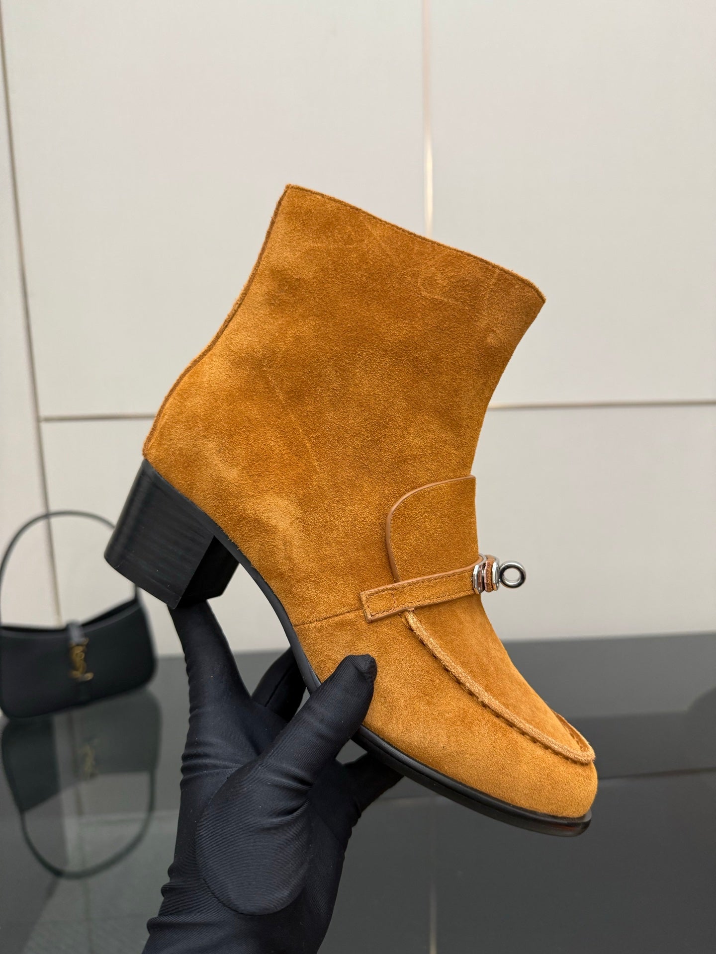 Tan suede ankle boot with buckle strap and block heel, close-up on one boot.