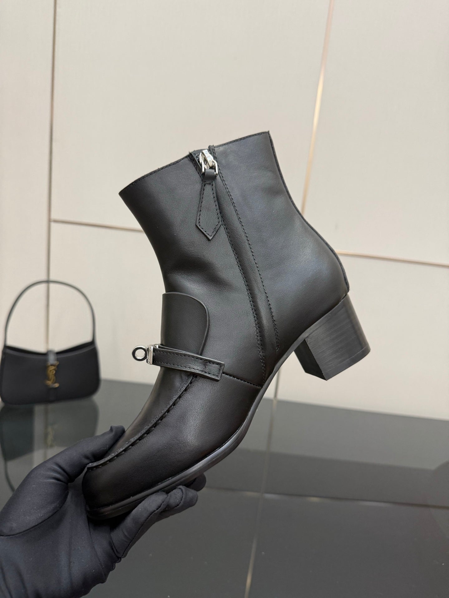 Hermes ladies black leather ankle boot held in hand, ankle strap with silver tab