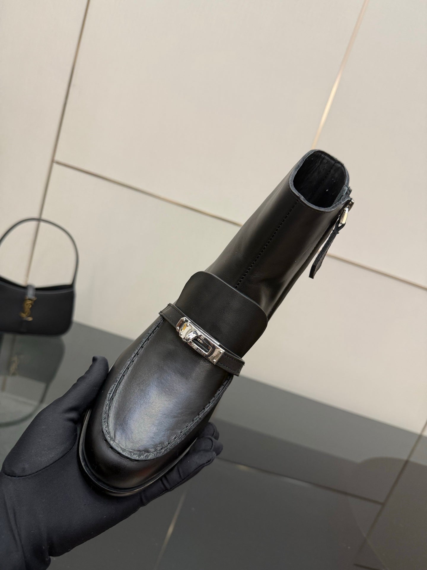 Hermes ladies black leather ankle boot held in hand, side zipper detail