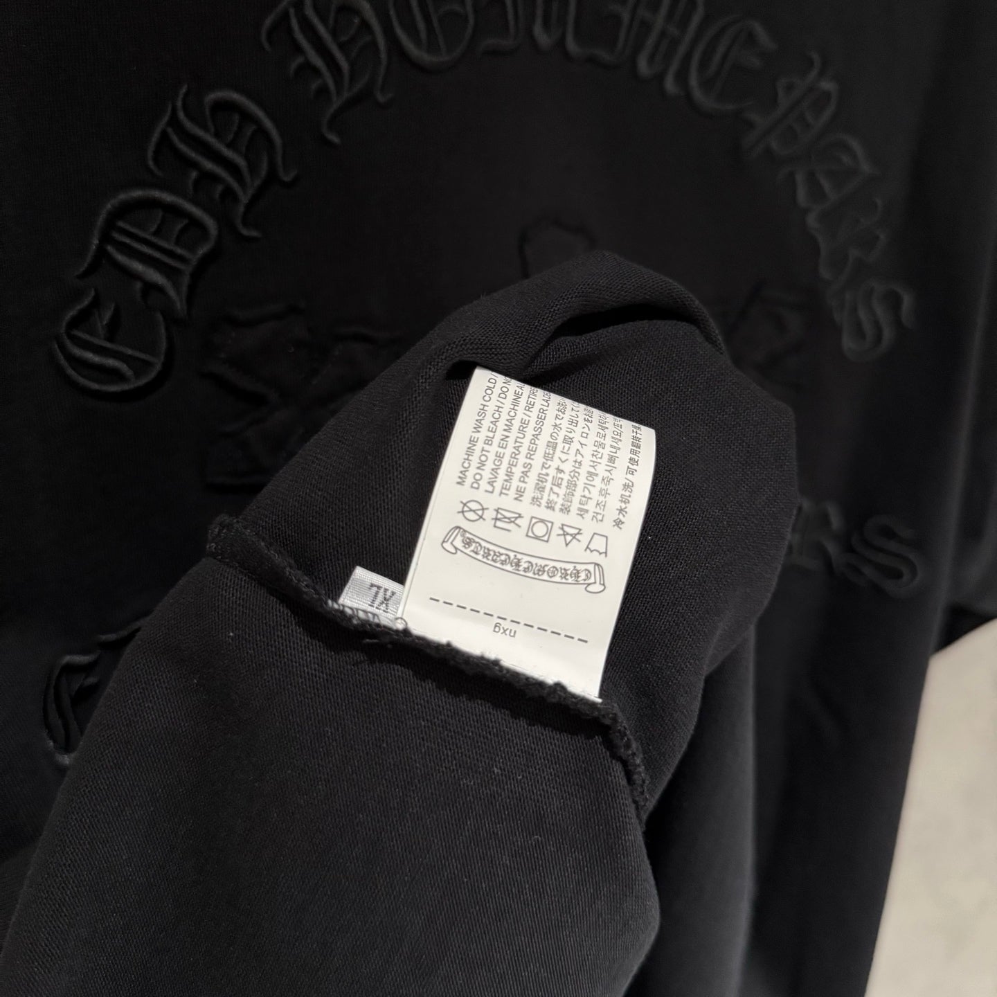 Black sweatshirt sleeve with white care label and stitched seam detail
