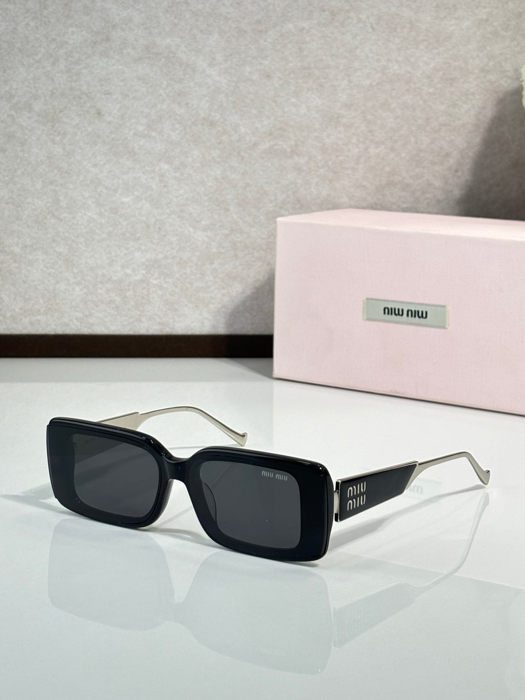 MiuMiu sunglasses with black square frames and gold-toned metal arms