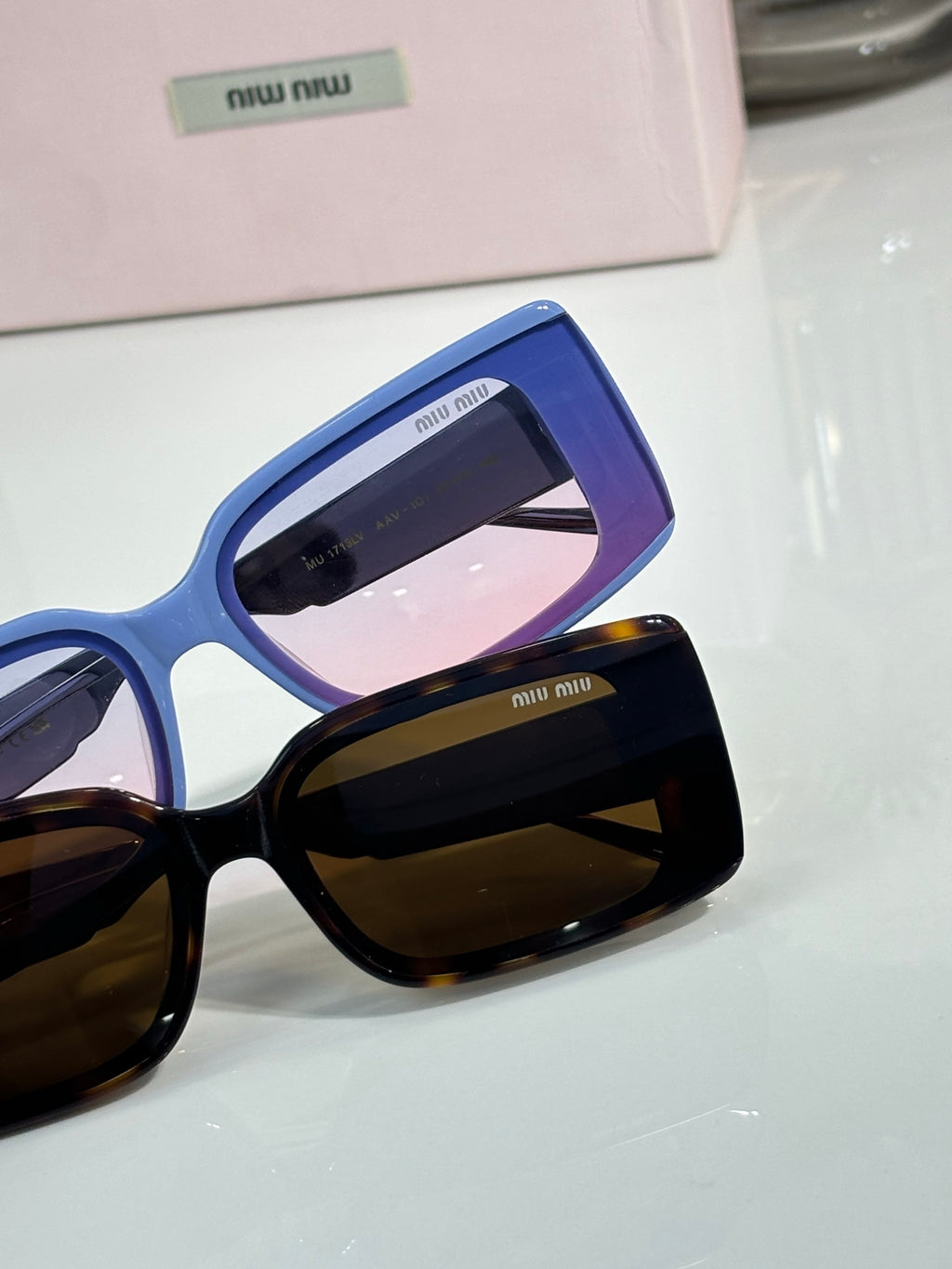 MiuMiu sunglasses close-up with blue square frames and dark tinted lenses