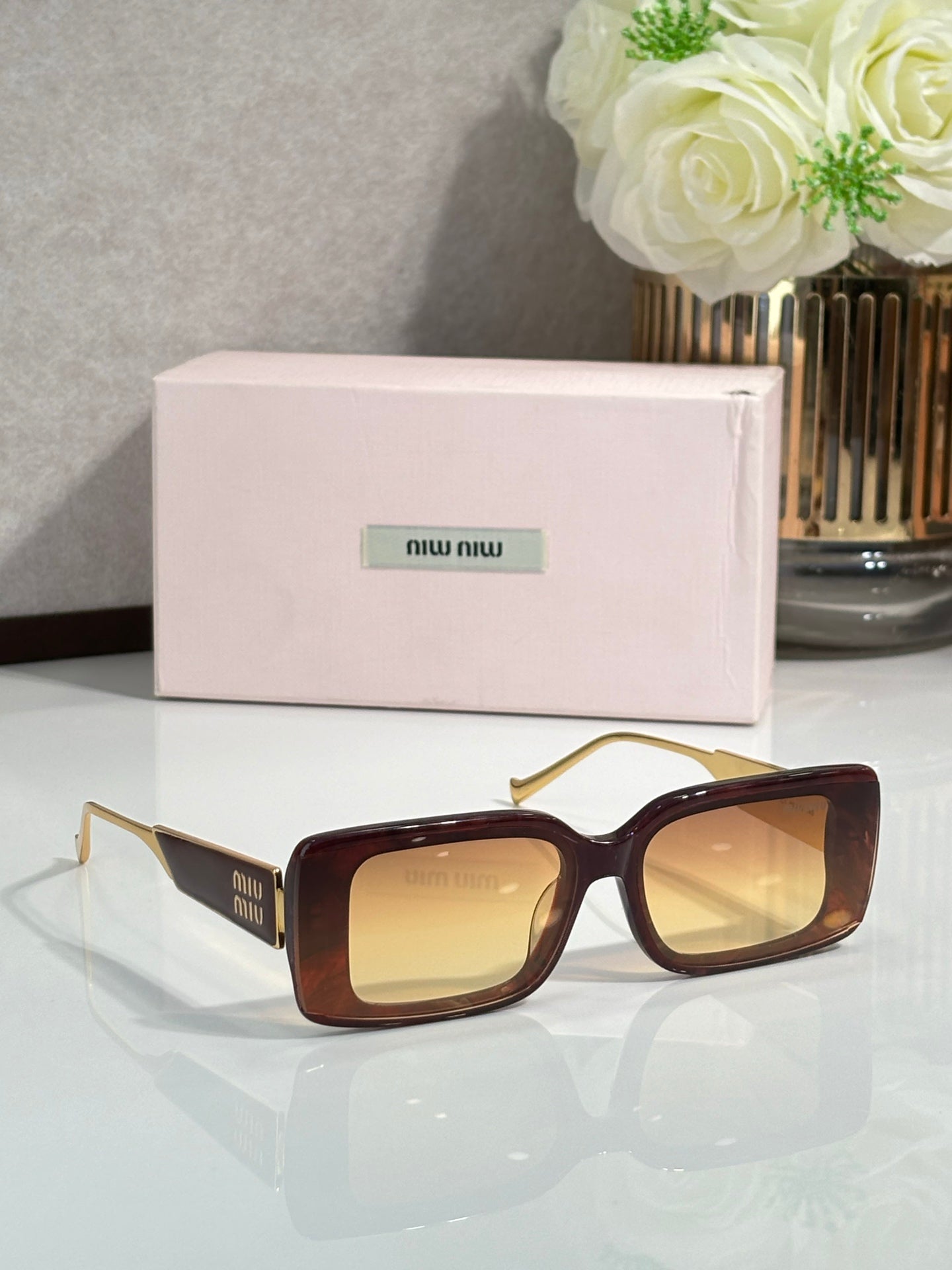 MiuMiu sunglasses with dark red-brown square frames and gold-toned metal arms