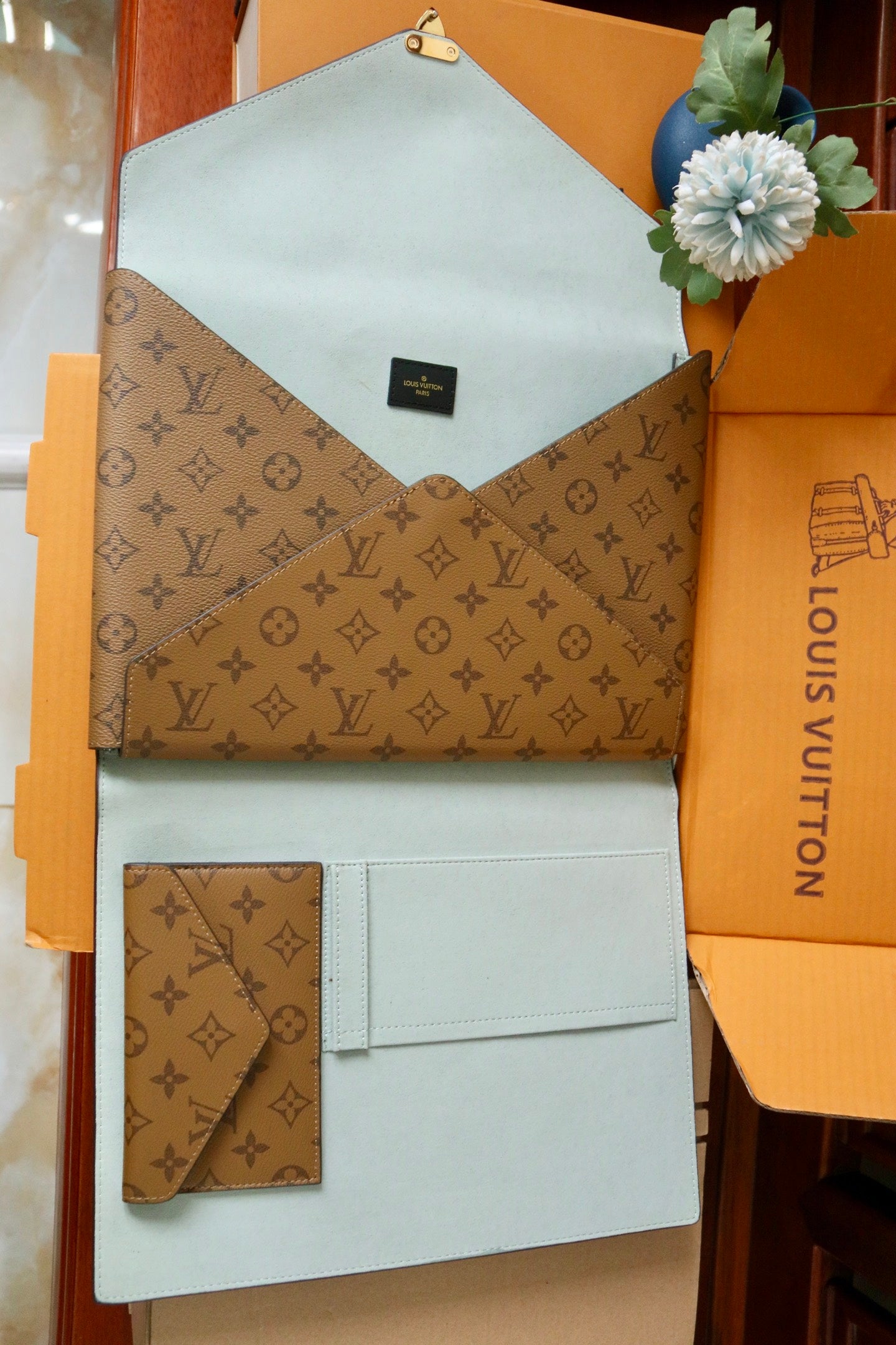 Louis Vuitton small bag with light blue base, brown monogram flap, and card holder