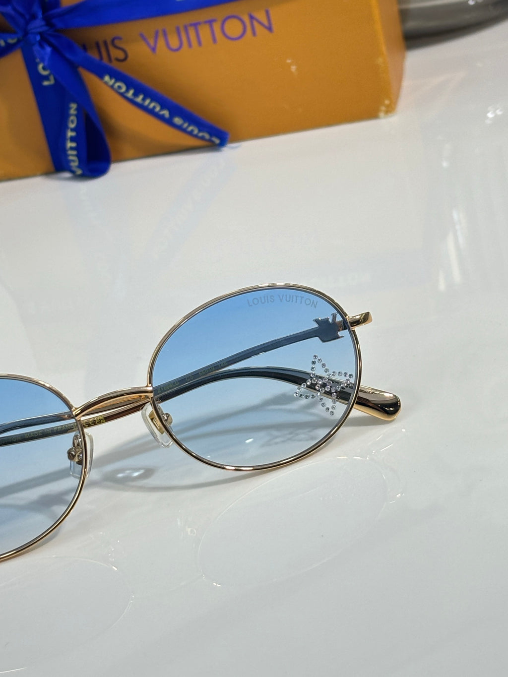Louis Vuitton round sunglasses close-up with blue lenses and gold frame
